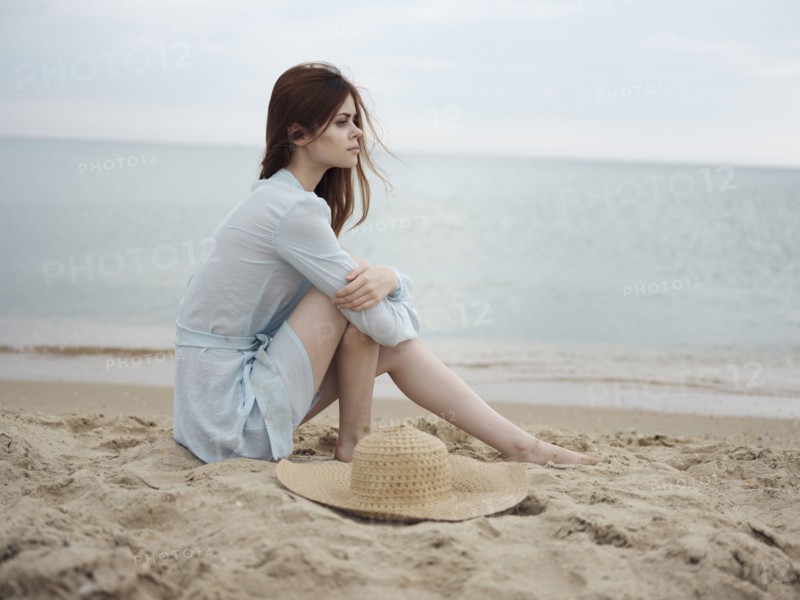 Pensive Caucasian woman sitting on beach