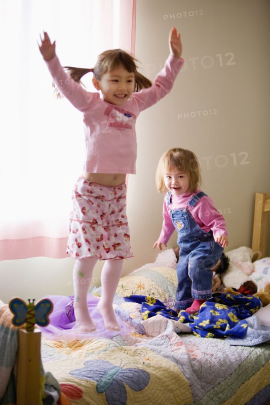 Two girls jumping on bed