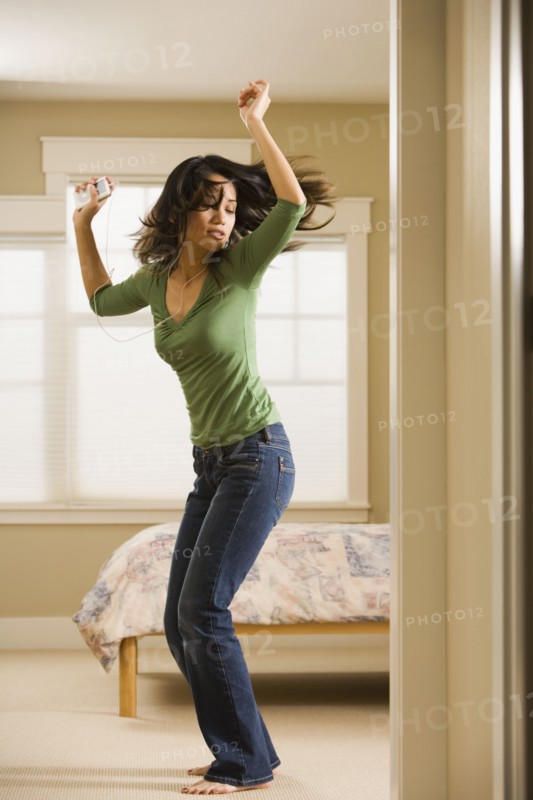 Woman dancing in bedroom while listening to music