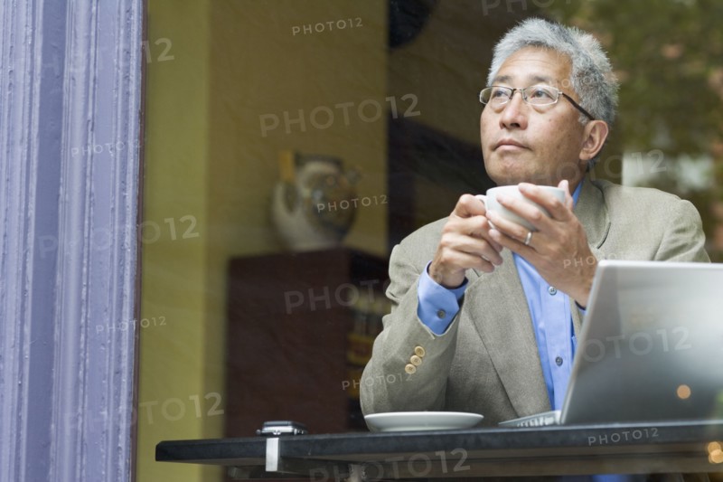 Senior Asian businessman with laptop at cafe