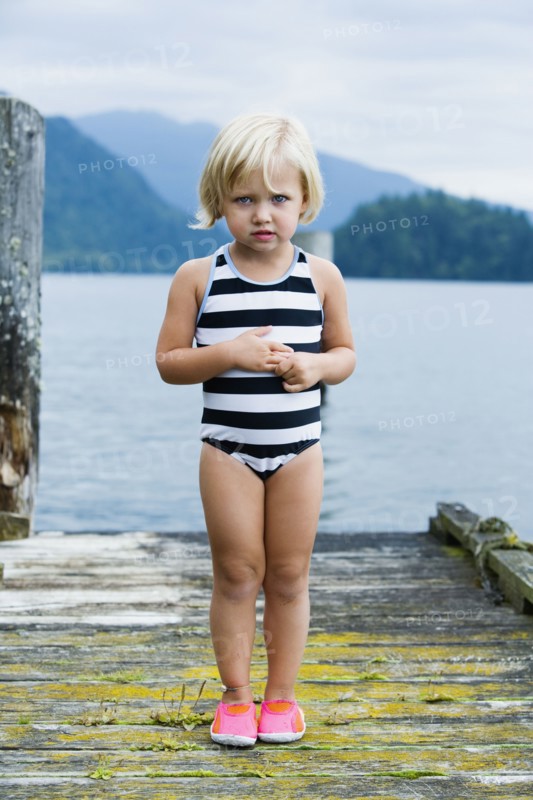 Young girl in bathing suit standing on wooden pier