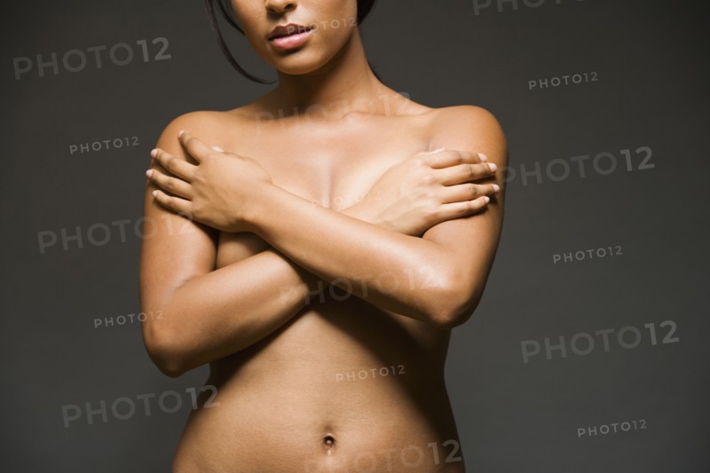 Nude Hispanic woman with arms covering breasts
