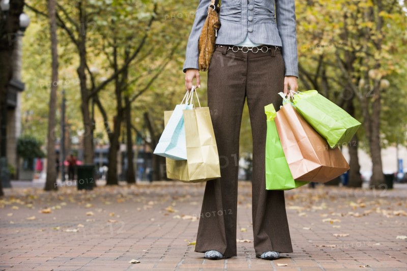 Woman holding shopping bags in urban park