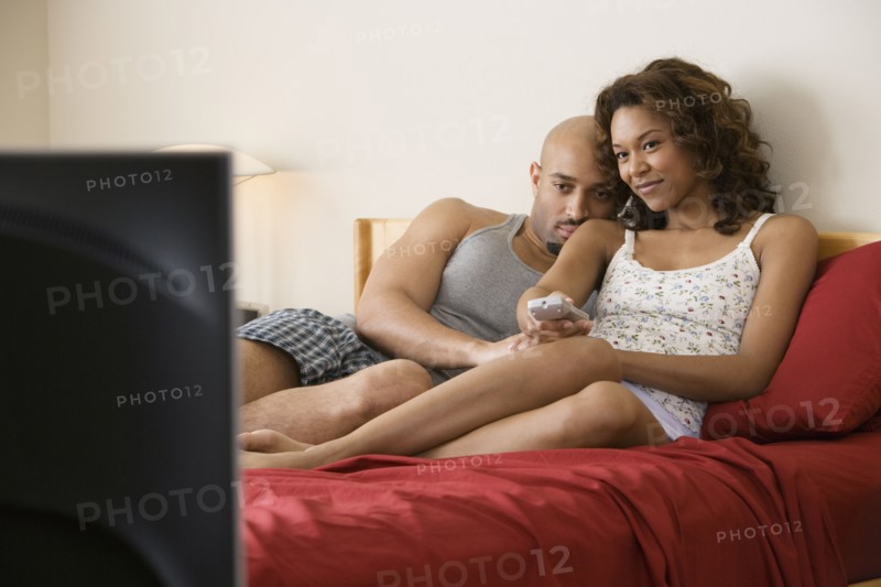 African couple cuddling in bed
