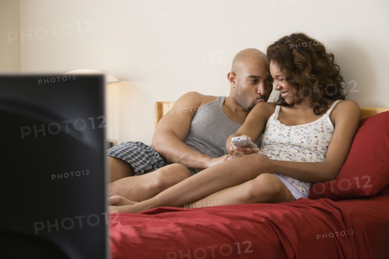 African couple cuddling in bed