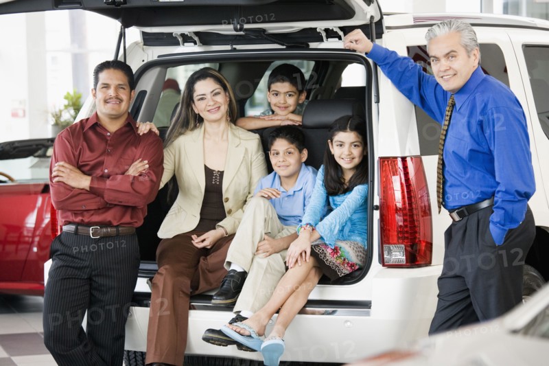 Hispanic family with salesman at car dealership