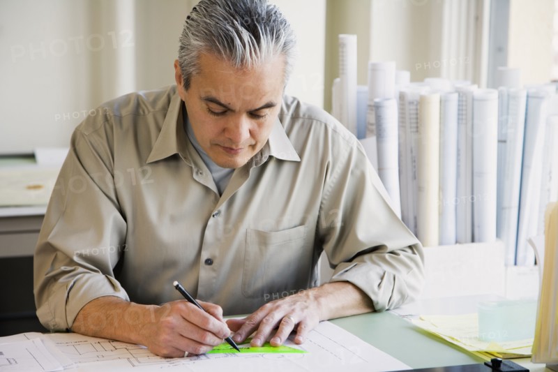 Hispanic male architect writing at desk