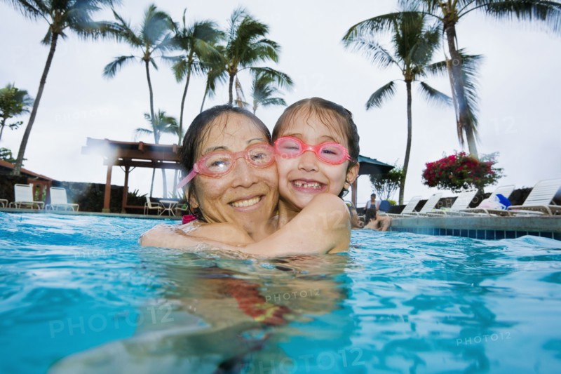 Asian mother and daughter hugging in swimming pool