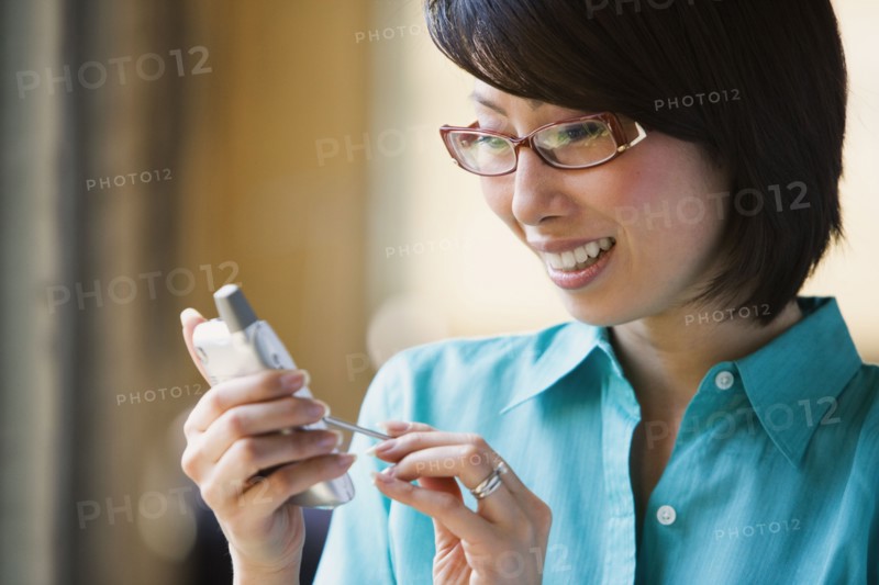 Asian woman smiling and using electronic organizer