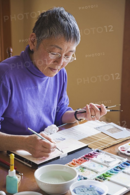Asian woman painting at table