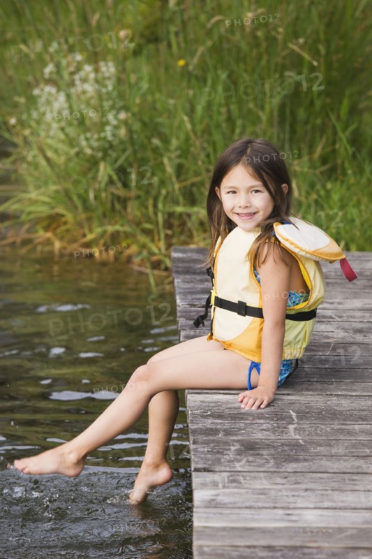 Asian girl in life jacket on dock