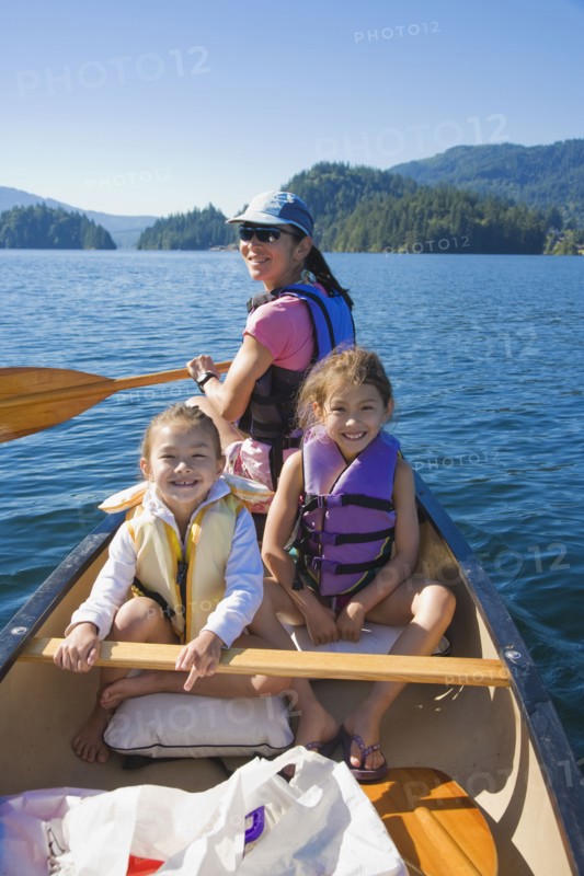Mother and daughters rowing canoe on lake