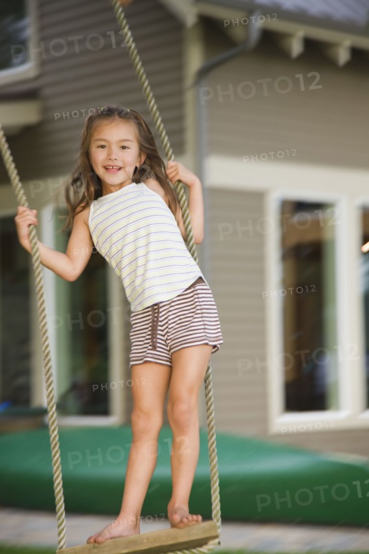 Asian girl swinging on rope swing