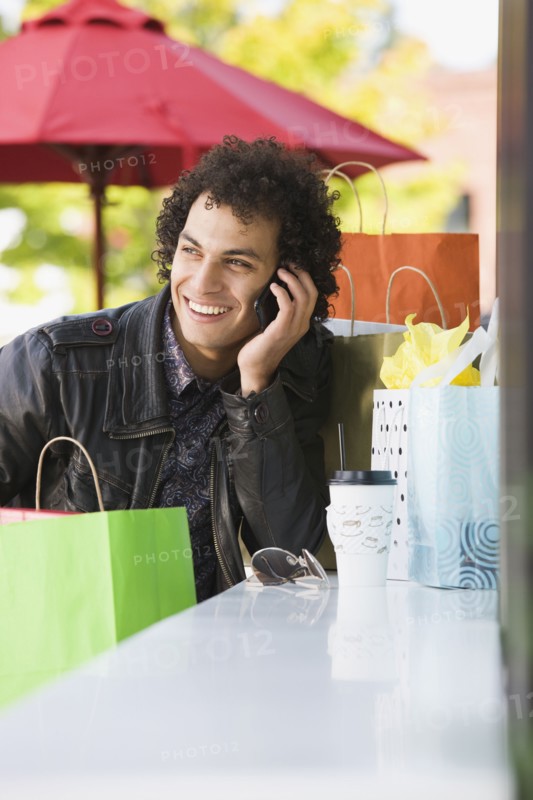 Middle Eastern man with shopping bags talking on cell phone