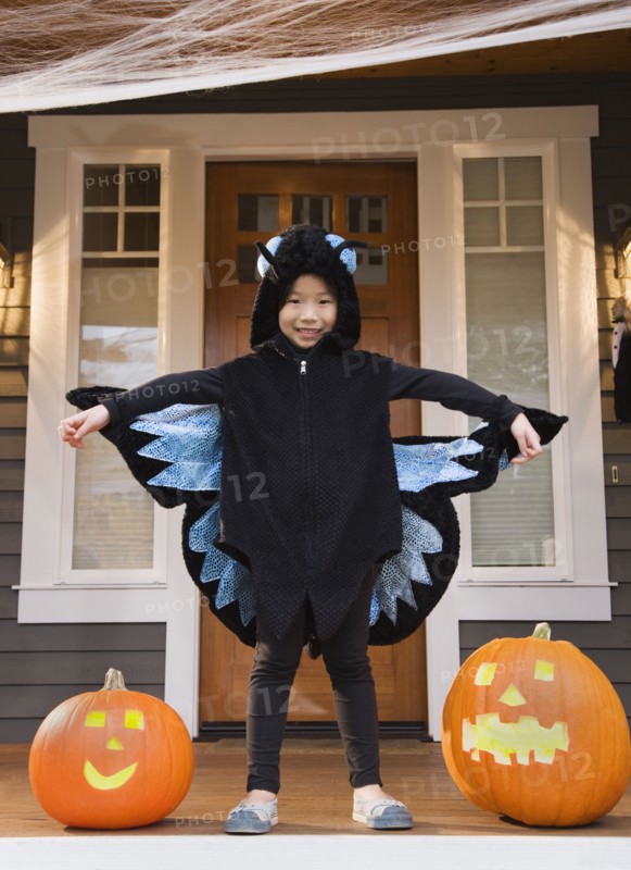 Young Chinese girl in butterfly costume with Halloween pumpkins