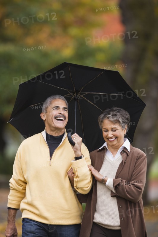 African couple walking with umbrella in autumn