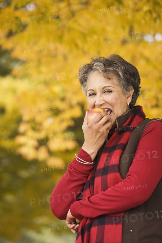 African woman eating apple outdoors in autumn