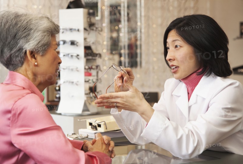 Korean optician showing eyeglasses to customer