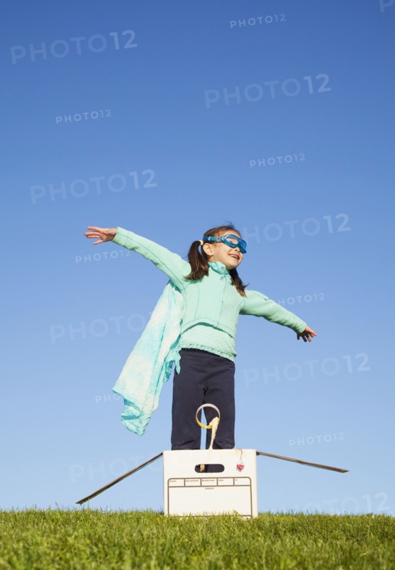 Mixed race girl wearing cape and standing in box