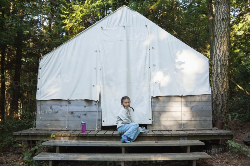 Mixed race girl sitting near tent