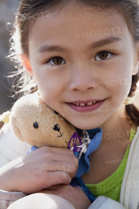 Mixed race girl holding teddy bear