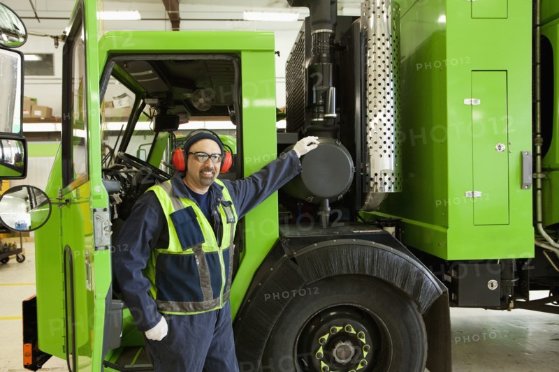 Pacific Islander man standing by garbage truck