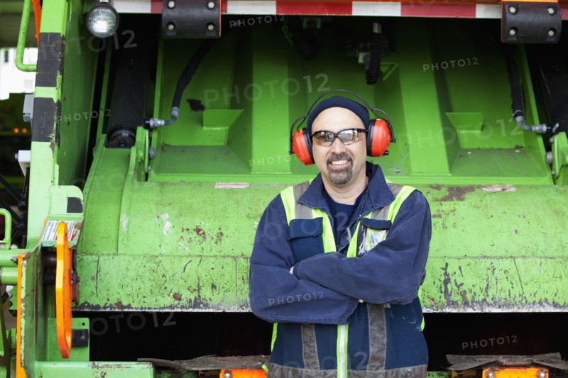 Pacific Islander man standing by garbage truck