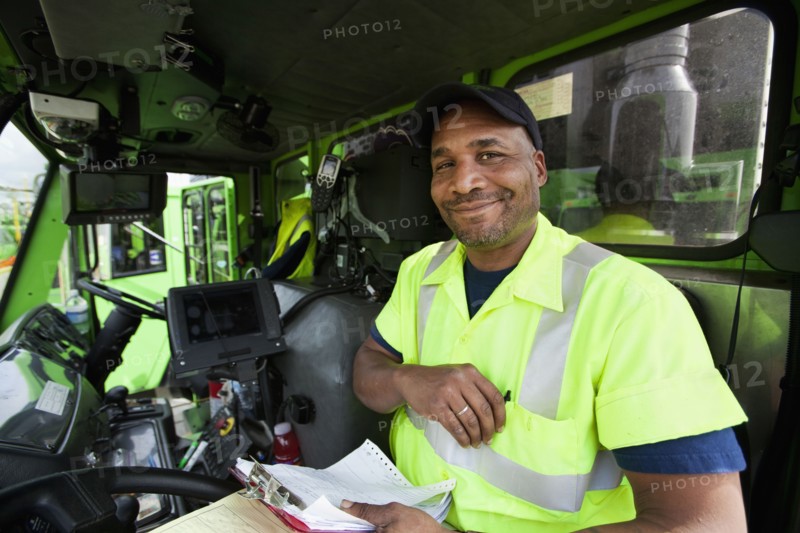 African American man driving garbage truck