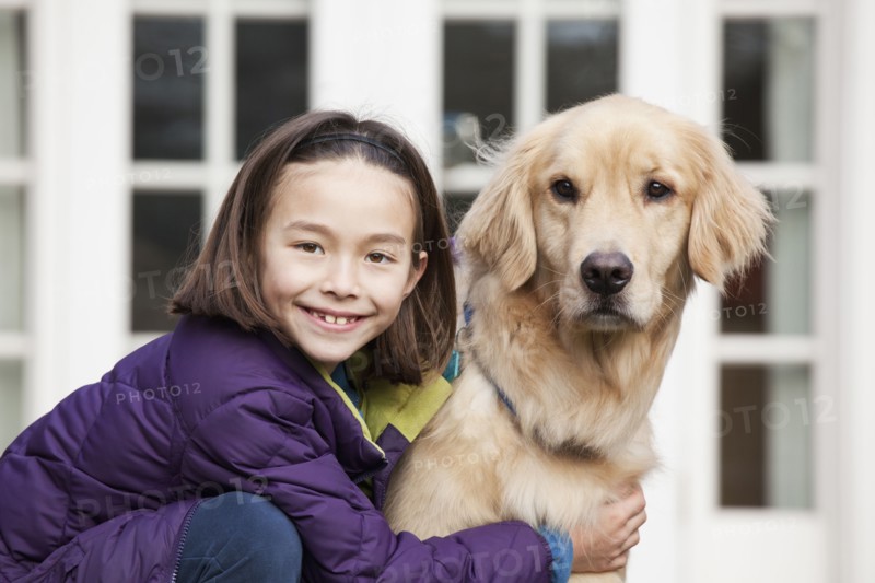 Mixed race girl hugging Golden retriever