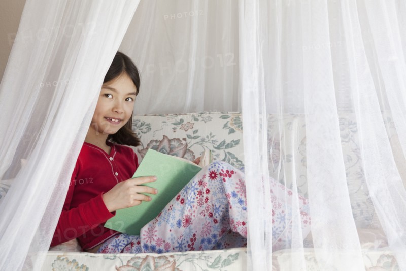Mixed race girl reading on sofa