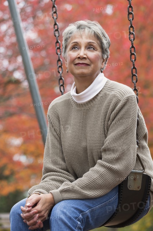 Mixed race woman on swing in park