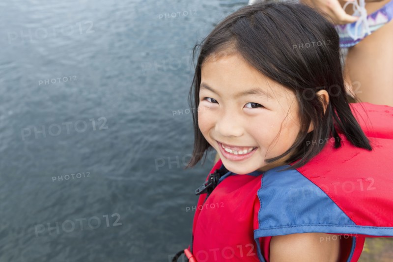 Mixed race girl smiling by lake