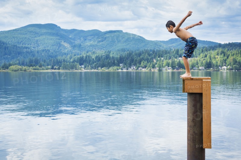 Korean boy jumping off platform into lake