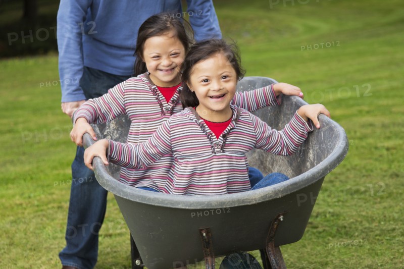 Twins with Down's Syndrome smiling in wheelbarrow