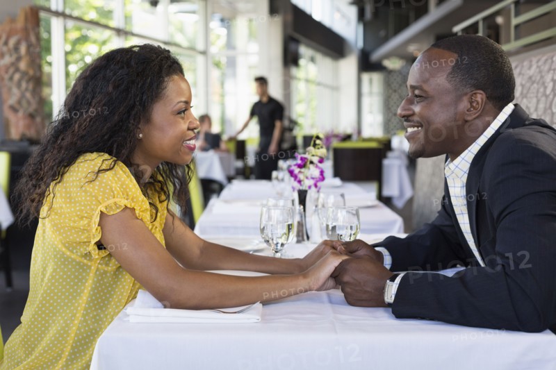 African American couple holding hands in restaurant