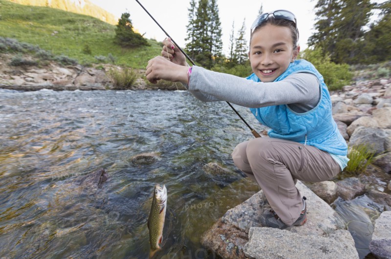 Mixed race girl fishing in river
