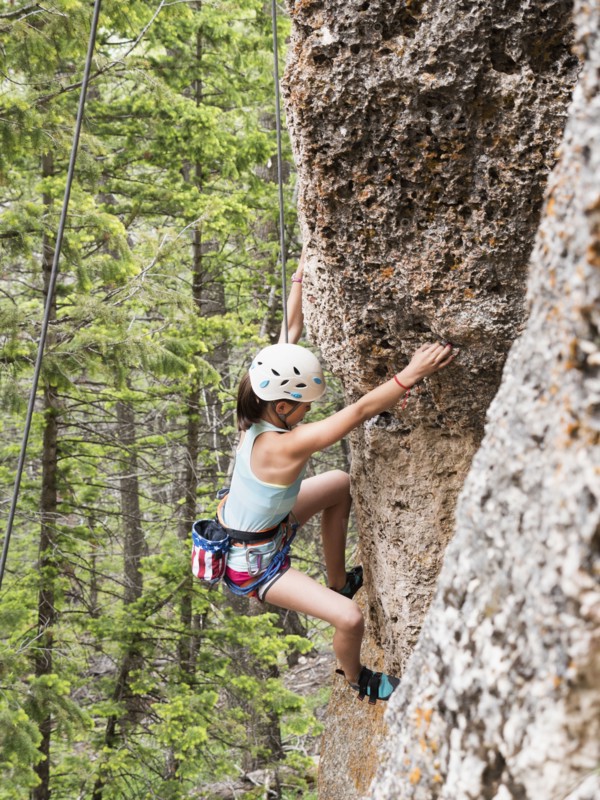 Mixed race girl climbing steep cliff