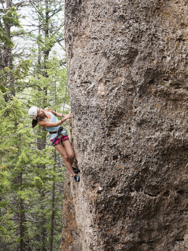 Mixed race girl climbing steep cliff