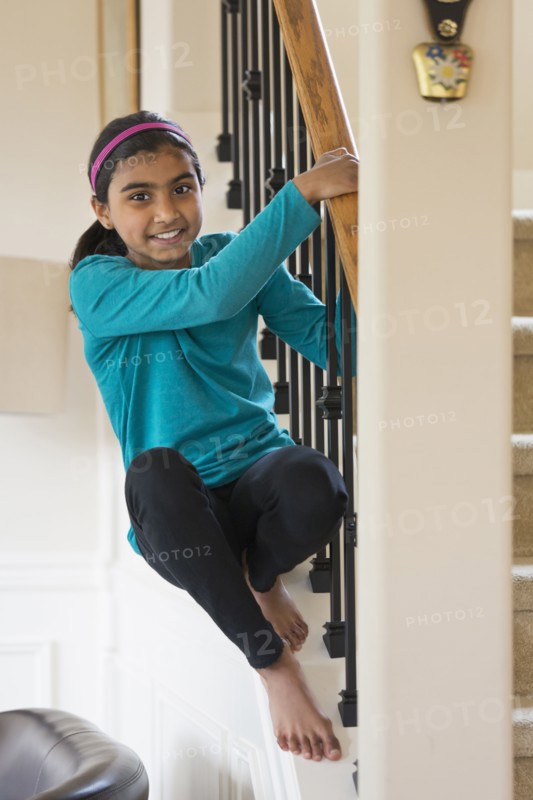 Indian girl climbing on staircase banister