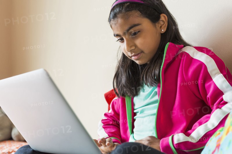 Indian girl using laptop on bed