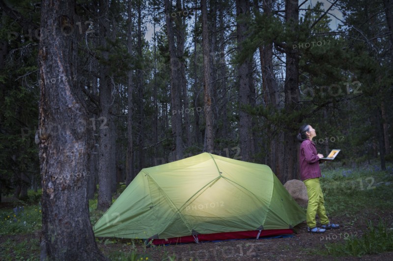 Japanese woman using laptop at campsite
