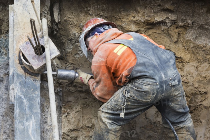 Caucasian worker drilling at construction site