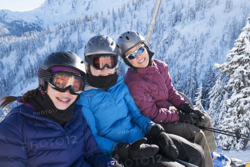 Mother and daughters riding ski lift