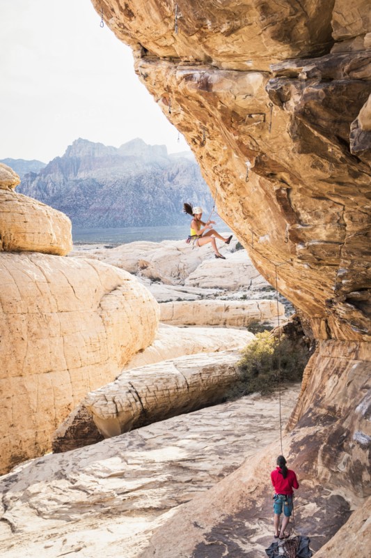 Mother belaying daughter rock climbing on cliff