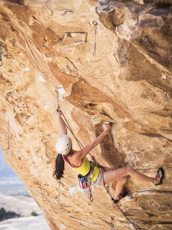 Mixed race girl rock climbing on cliff