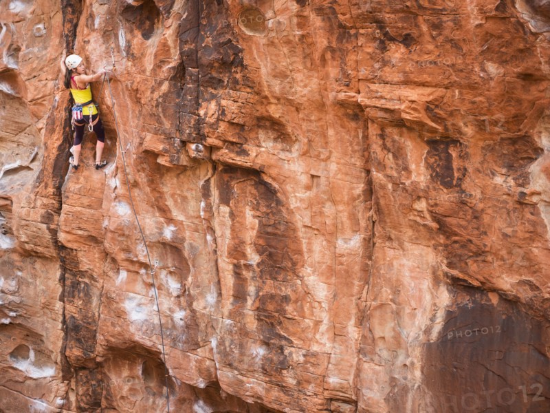 Mixed race girl rock climbing on cliff