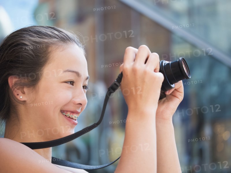 Mixed Race girl photographing outdoors with digital camera
