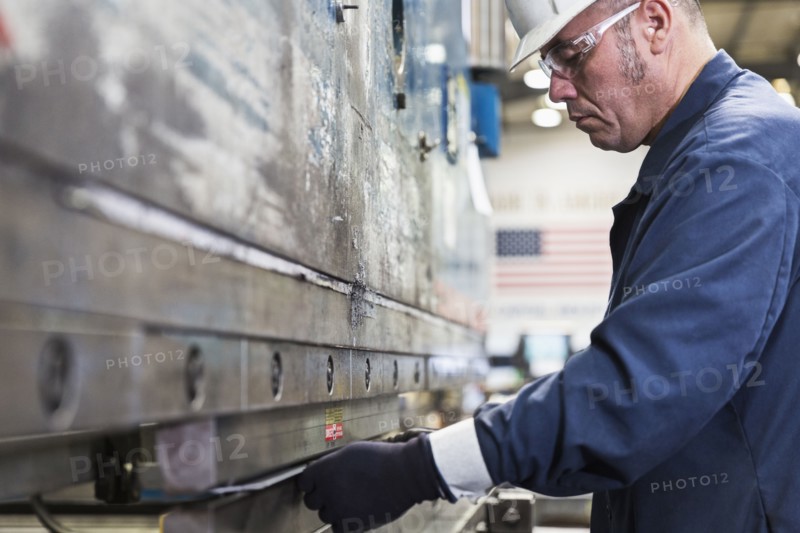 Hispanic worker fabricating metal in factory