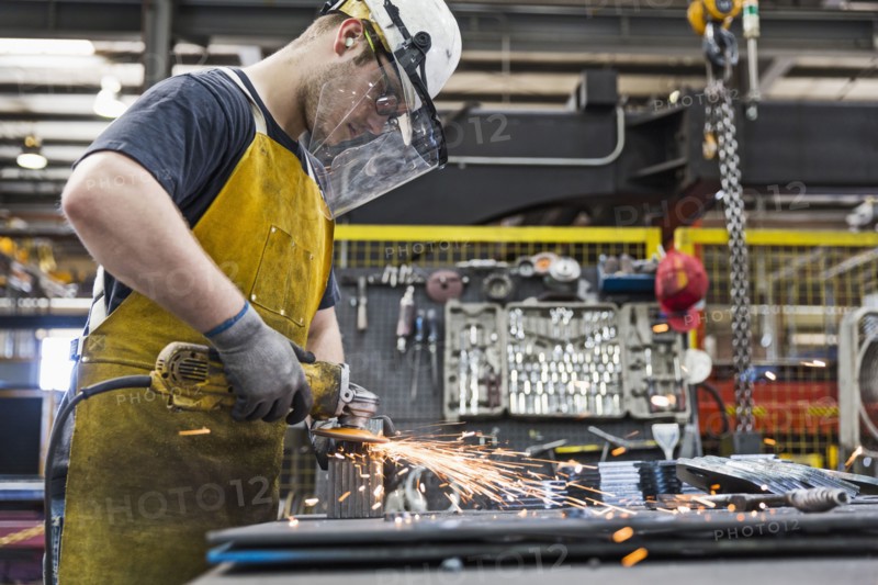 Caucasian worker grinding metal in factory