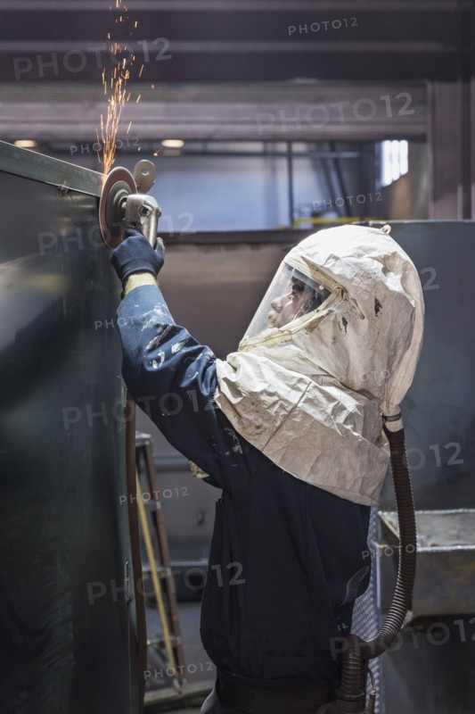 Caucasian worker grinding metal container in factory